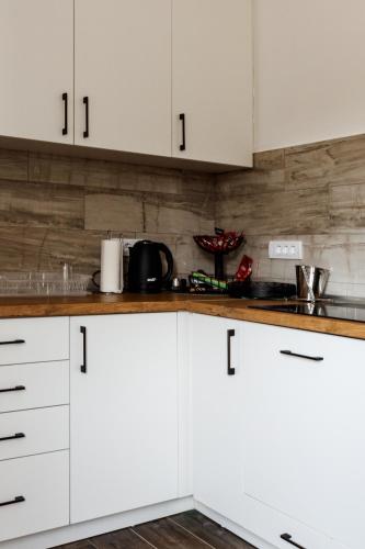 a kitchen with white cabinets and wooden counter tops at Vila Roda in Banja Luka