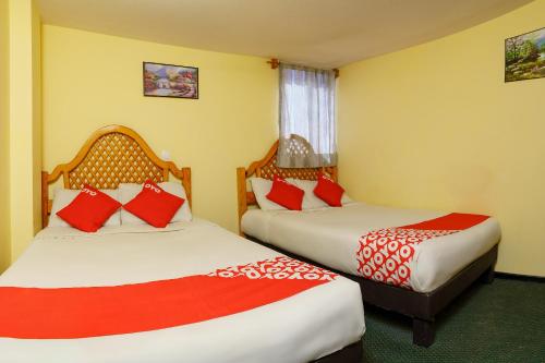 two beds in a hotel room with red and white pillows at OYO Hotel Bugambilia, San Luis Potosí in San Luis Potosí