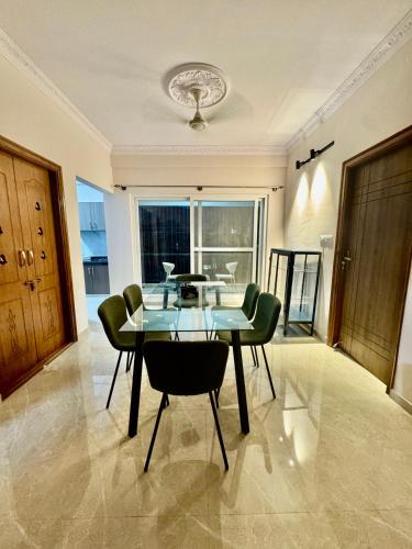 a dining room with a glass table and green chairs at Sliceinn Sylva, Wilson Garden, Bangalore in Bengaluru