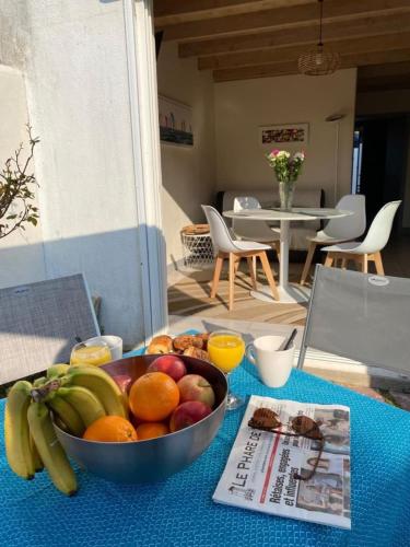- un bol de fruits sur une table avec un journal dans l'établissement Cozy retreat near the beach terraces and parking, à La Flotte