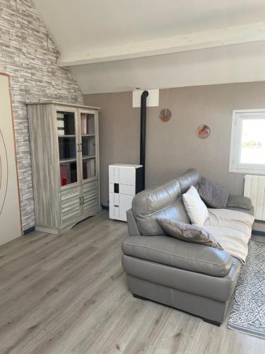a living room with a leather couch and a window at La maison du Bas in Naours