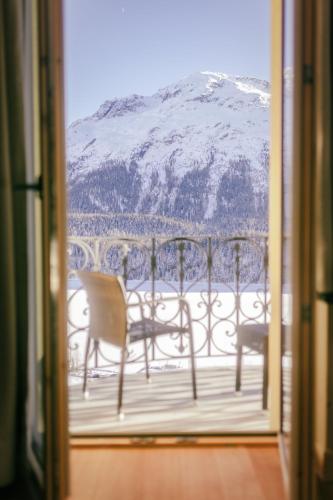 a balcony with a table and chairs and a snow covered mountain at Kulm Hotel St. Moritz in St. Moritz