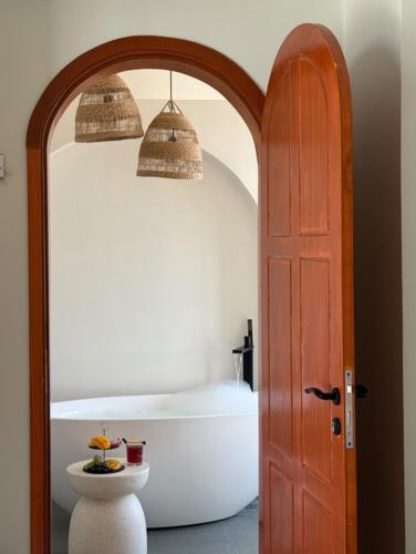 a bathroom with a tub and a wooden door and a toilet at zahr albun villa in Al Raka