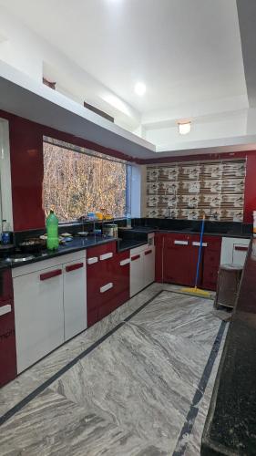 a kitchen with red and white cabinets and a window at Himalayan Gypsie Hotels in Goichran