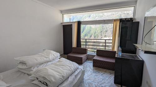 a bedroom with two beds and a large window at Himalayan Gypsie Hotels in Goichran