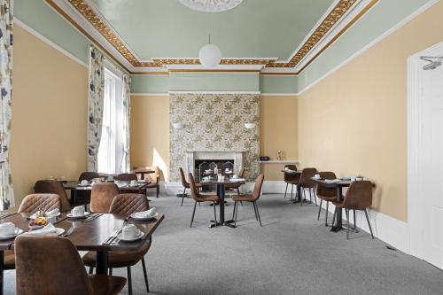 a dining room with tables and chairs and a fireplace at Imperial Plymouth in Plymouth