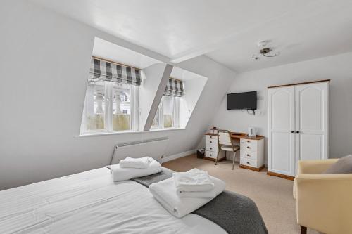 a bedroom with a bed and a desk and windows at Imperial Plymouth in Plymouth