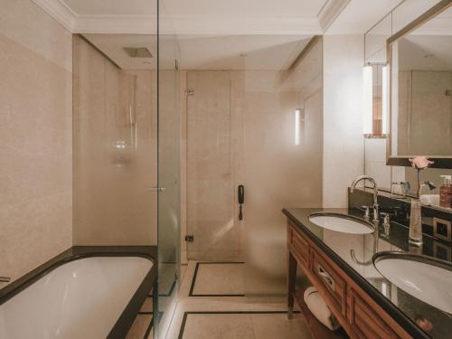 a bathroom with a tub and two sinks and a shower at Kulm Hotel St. Moritz in St. Moritz