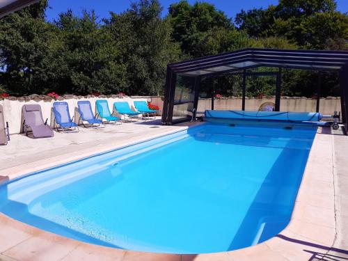 - une piscine avec des chaises et un pavillon dans l'établissement La Julerie, 4 Gîtes en Campagne avec Piscine, à Corseul