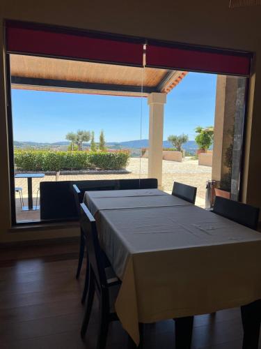 a dining room with a table and a large window at Tranca da Barriga - Casa do Vinho by Quinta De São Tiago in Covilhã