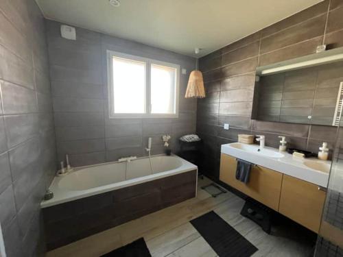une salle de bain avec une grande baignoire et deux lavabos dans l'établissement Charmante maison en bois, à Léon