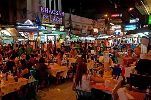 a crowd of people sitting at tables in a street at night at XX GO INN Khaosan - โกอินน์ ถนนข้าวสาร in Bangkok