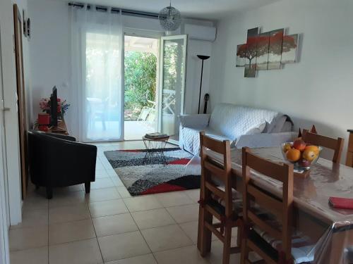 un salon avec une table et un canapé dans l'établissement Mini villa T2, 200 m de la plage, piscine chauffée, jardin, à Prunete