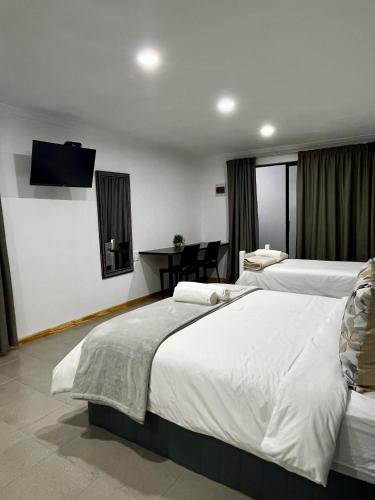 a hotel room with two beds and a flat screen tv at Cradock Guest House & Self Catering in Cradock