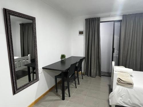 a room with a table and a mirror and a bed at Cradock Guest House & Self Catering in Cradock