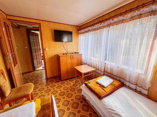 a bedroom with a bed and a table and a window at Leśna Osada Tęcza Jabłonowiec in Jabłonowiec