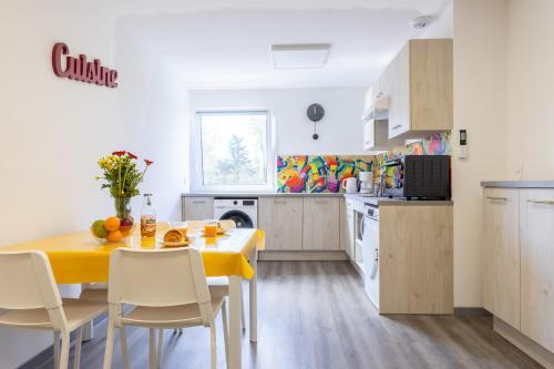 - une cuisine avec une table jaune et des chaises dans la chambre dans l'établissement L'îlot Narrossais - Idéal Curistes - 8, à Narrosse