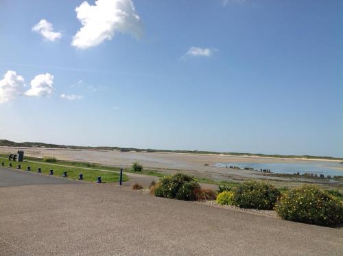a road next to a beach with a body of water at Le Caribou d'Eva in Portbail