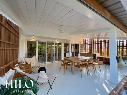 a living room with a table and chairs on a patio at HILO Villa Lagon de l'Hermitage Nomade in L'Ermitage-Les-Bains