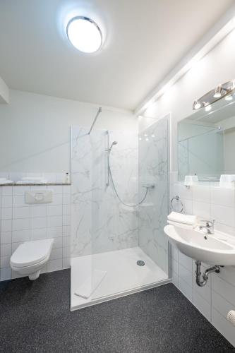 a white bathroom with a sink and a shower at Hotel Hanseport Hamburg in Hamburg
