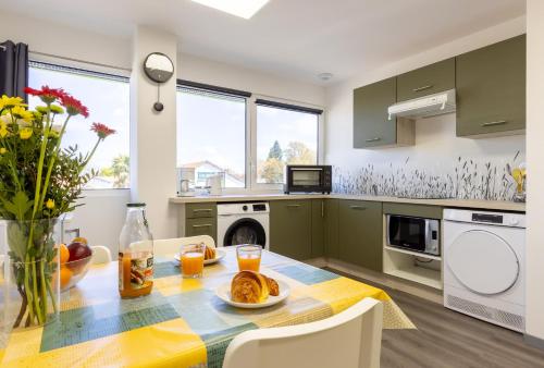 une cuisine avec des placards verts et une table avec de la nourriture. dans l'établissement L'îlot Narrossais - Idéal Curistes - 3, à Narrosse