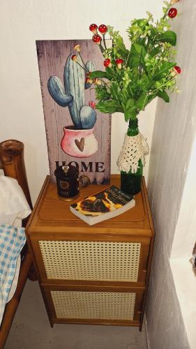 a table with a vase of flowers and a picture of a cactus at Bahay Bakasyunan in Lubao near Pradera Verde in Lubao