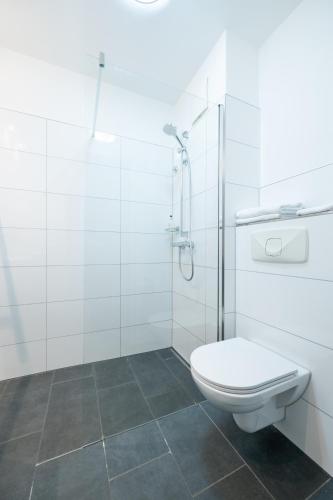 a white bathroom with a toilet and a shower at Hotel Hanseport Hamburg in Hamburg