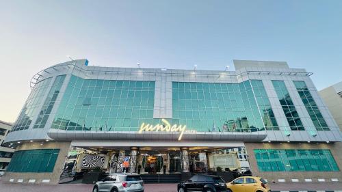 a large glass building with cars parked in front of it at Sunday Hotel Holiday international Dubai in Dubai