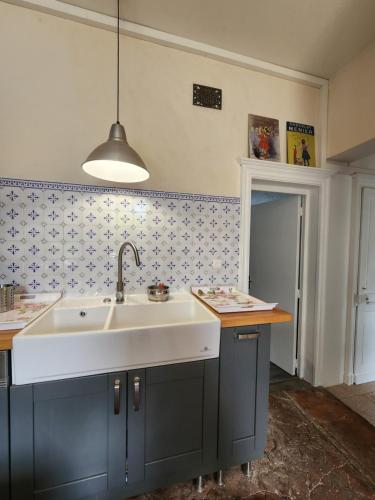 a kitchen with a white sink and blue cabinets at Authentique villa de campagne in Saint-Vaast-Dieppedalle
