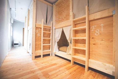 a room with two bunk beds and wooden floors at Noboribetsu Guest House AKA & AO in Noboribetsu