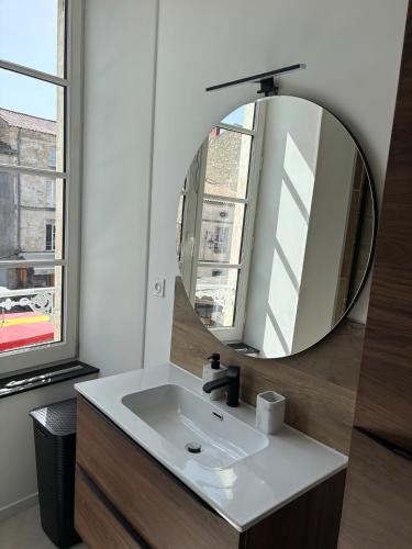a bathroom with a sink and a mirror at Appartement plein coeur de ville in Fontenay-le-Comte
