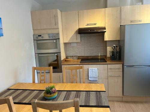 une cuisine avec une table, des chaises et un réfrigérateur dans l'établissement 2 Bedroom Townhouse near Cardiff Bay and City Centre with Garden and Parking, à Cardiff