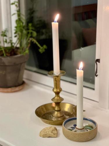 two candles on a table with a gold candlestick at Hotel Klostergaarden in Allinge
