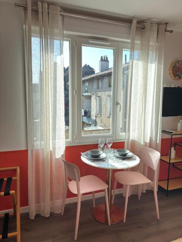 une salle à manger avec une table et des chaises et une fenêtre dans l'établissement Rose Roanne centre-ville - Parking & Clim, à Roanne