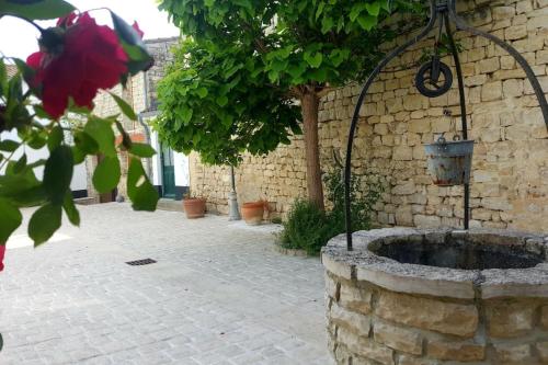 une fontaine en pierre dans une cour avec un arbre dans l'établissement Peaceful house with a sunny courtyard and pool, à Sainte-Marie de Ré