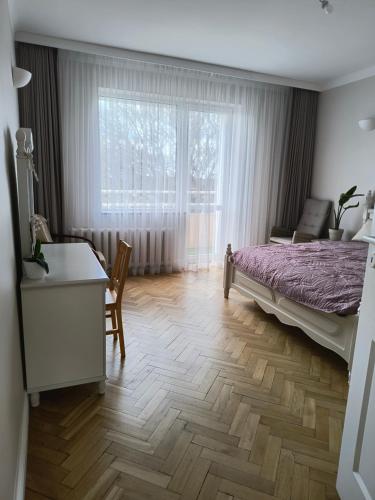 Un dormitorio con una cama y un escritorio y una ventana. en Apartament Mickiewicza, en Olsztyn