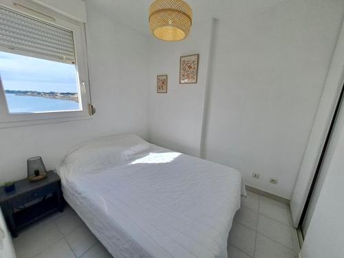 une chambre blanche avec un lit et une fenêtre dans l'établissement Les rives du lac, au Grau-du-Roi