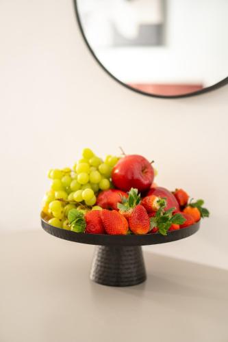 a plate of fruit on a stand in front of a mirror at Havatselet 19 By Isrentals in Jerusalem