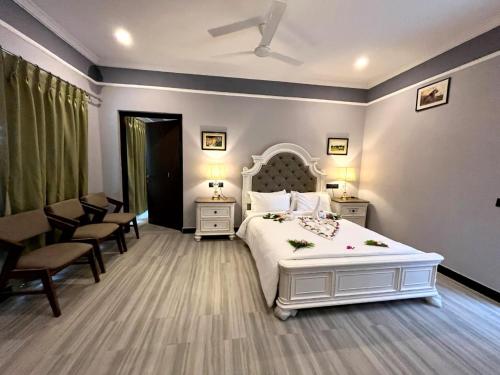 a bedroom with a large white bed and chairs at Tuli Orchid in Rāmtek