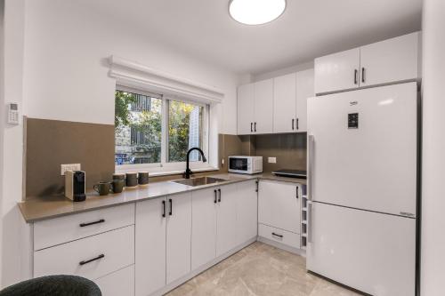 a kitchen with white cabinets and a white refrigerator at Havatselet 19 By Isrentals in Jerusalem