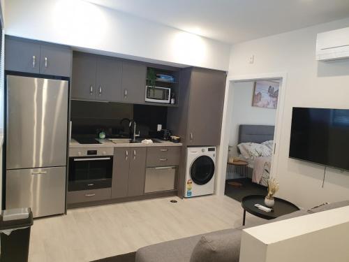 a kitchen with stainless steel appliances and a living room at Modern Central 1 Bedroom Apt in Lower Hutt