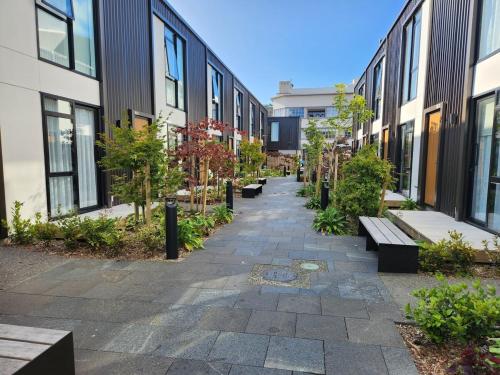 a walkway between buildings with benches and trees at Modern Central 1 Bedroom Apt in Lower Hutt