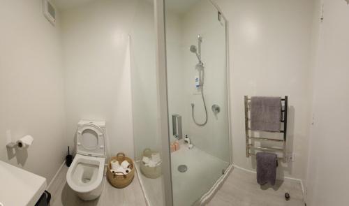 a white bathroom with a toilet and a shower at Modern Central 1 Bedroom Apt in Lower Hutt