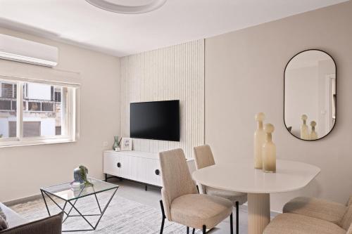 a white living room with a table and a mirror at Havatselet 19 By Isrentals in Jerusalem