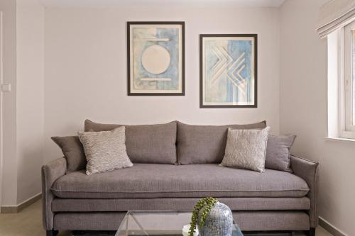 a couch in a living room with two pictures on the wall at Havatselet 19 By Isrentals in Jerusalem