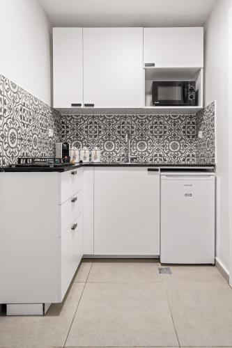 a kitchen with white cabinets and a tile wall at Havatselet 19 By Isrentals in Jerusalem