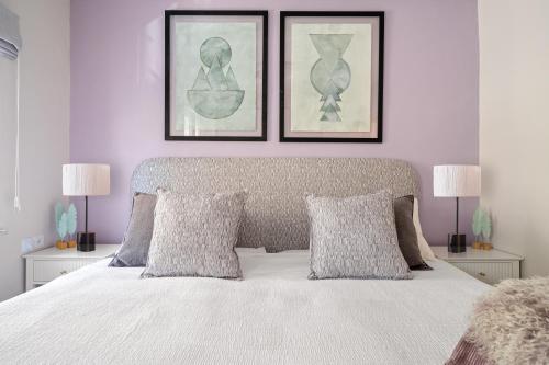 a bedroom with a white bed with two pictures on the wall at Havatselet 19 By Isrentals in Jerusalem