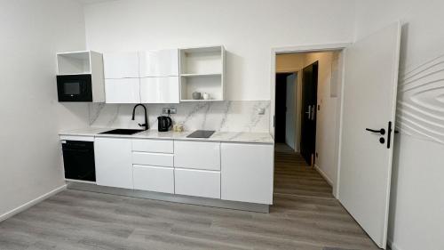 a white kitchen with white cabinets and a hallway at Villa Leopold - apartmánový dům in Karlovy Vary