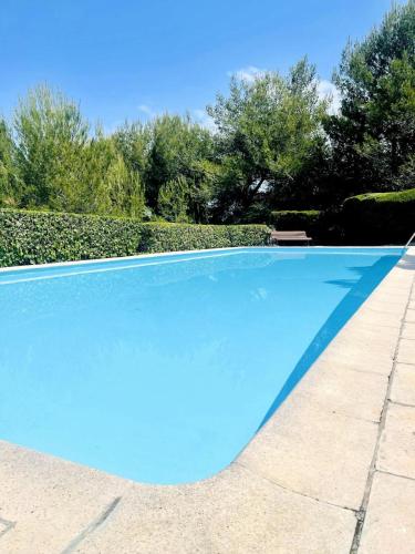 une grande piscine bleue avec des arbres en arrière-plan dans l'établissement Studio climatisé avec piscine-tennis-parking, à Villeneuve-Loubet