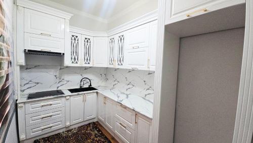 a white kitchen with white cabinets and a sink at Sultan hotel boutique in Andizhan
